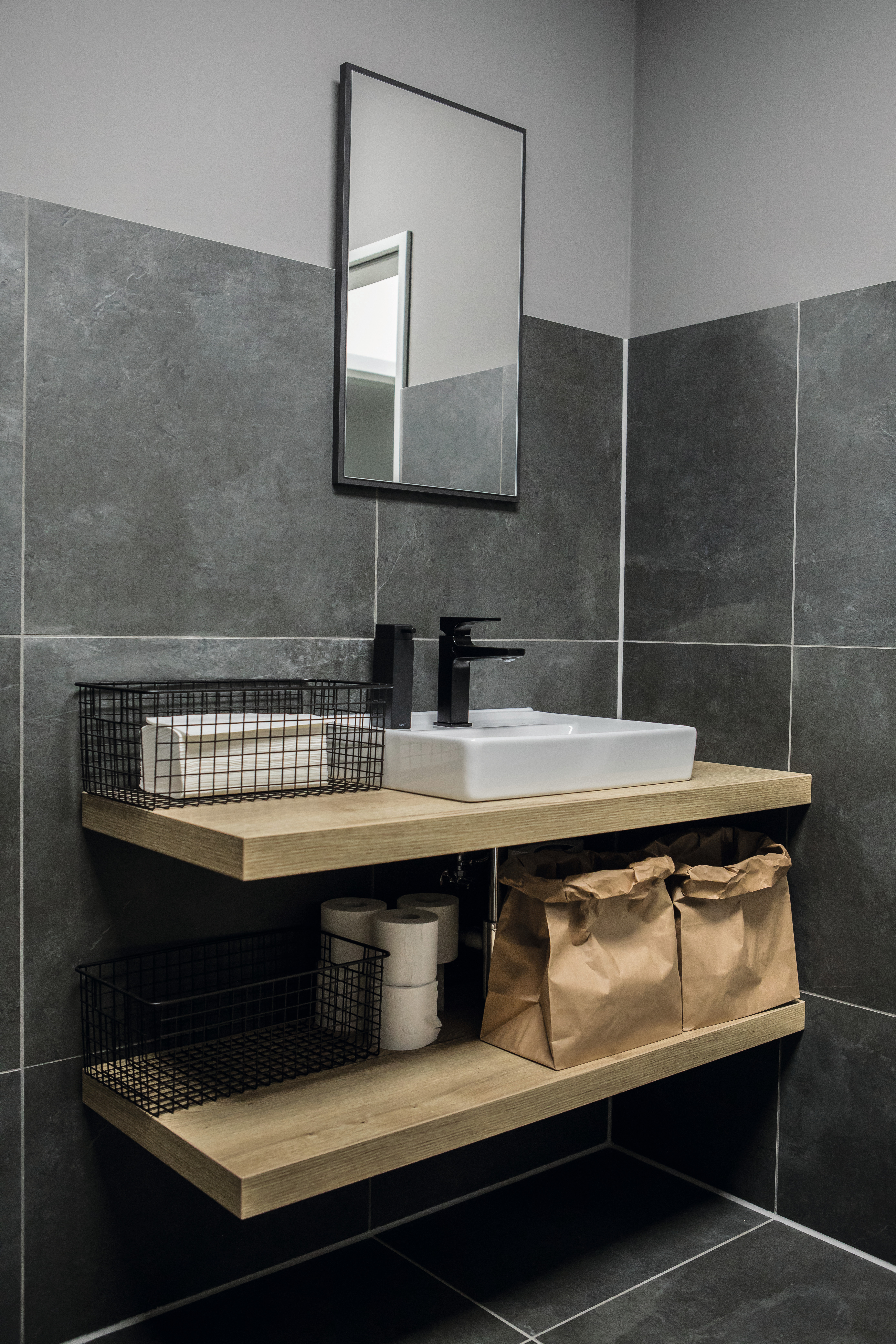 El diseño madera del lavabo culmina a la perfección el diseño en contraste entre blanco y negro.