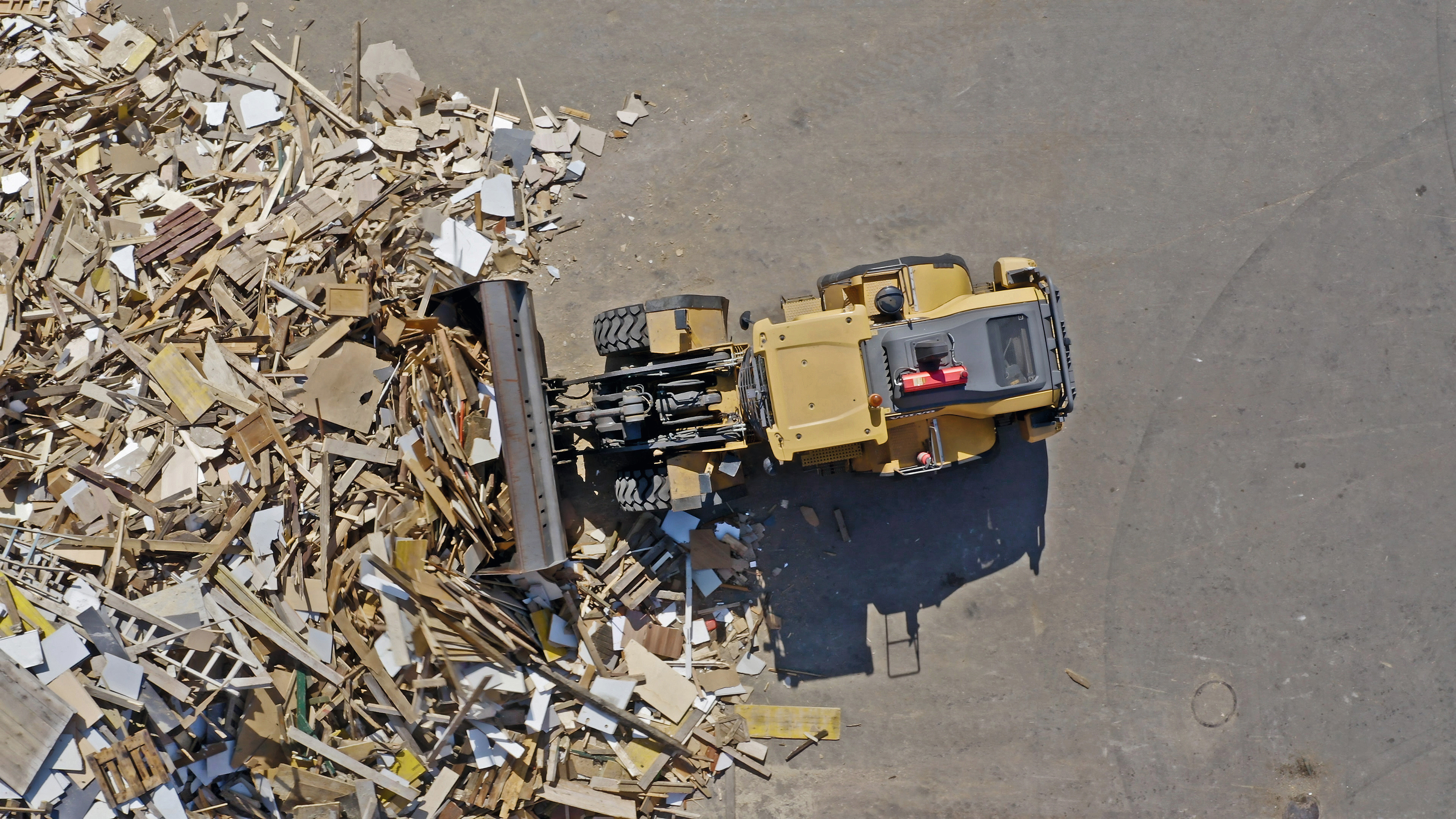 Excavator pushes recycled wood on the log yard