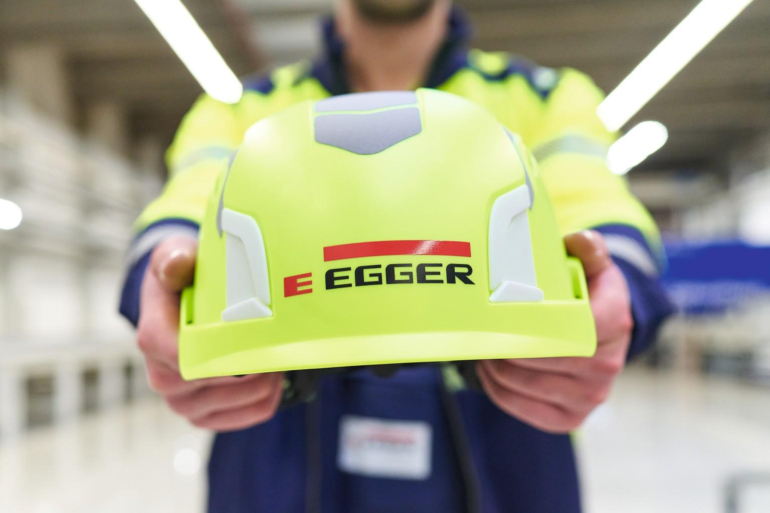 Angajat ține o cască cu logo-ul EGGER