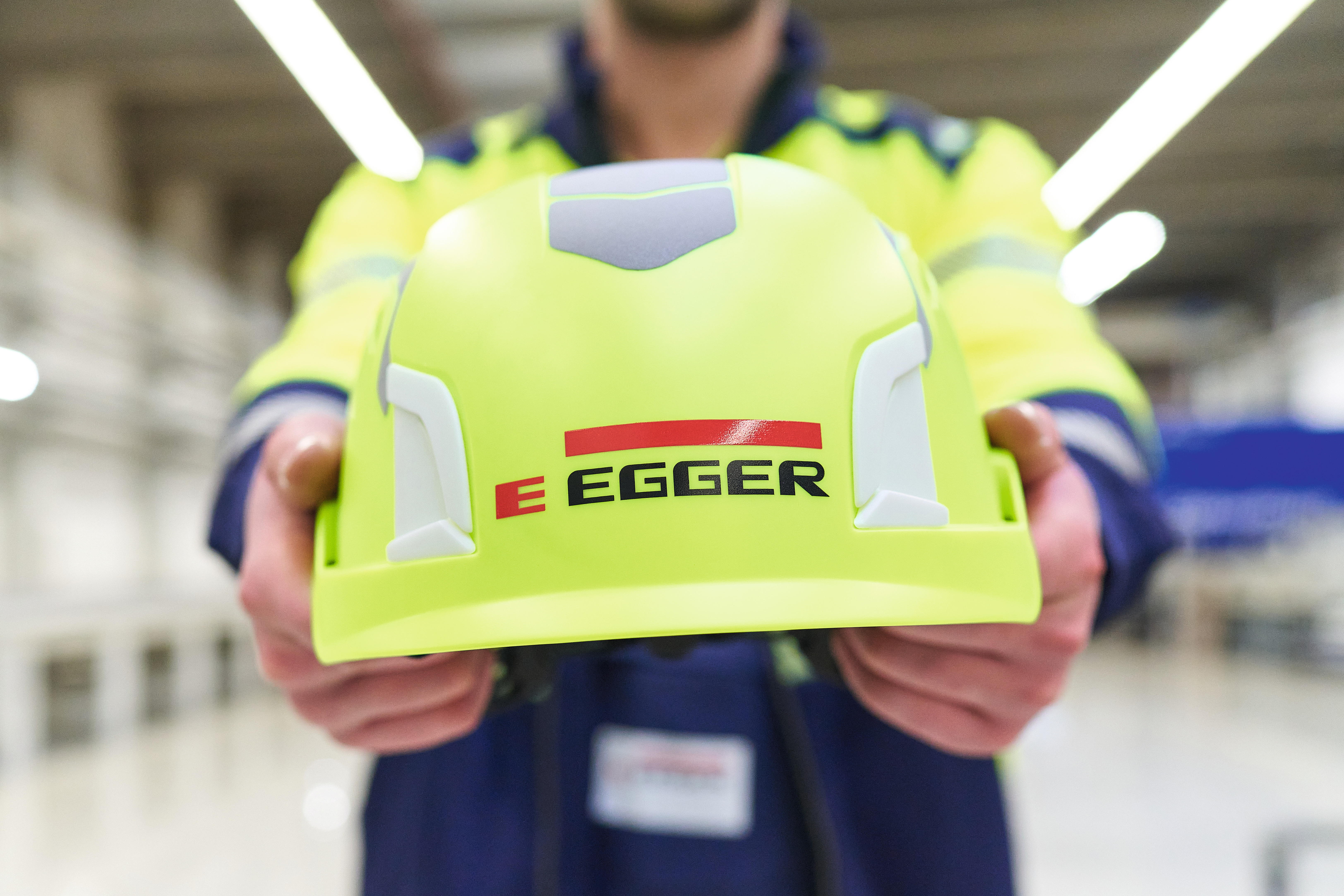 Pracownik trzyma kask z logo EGGER