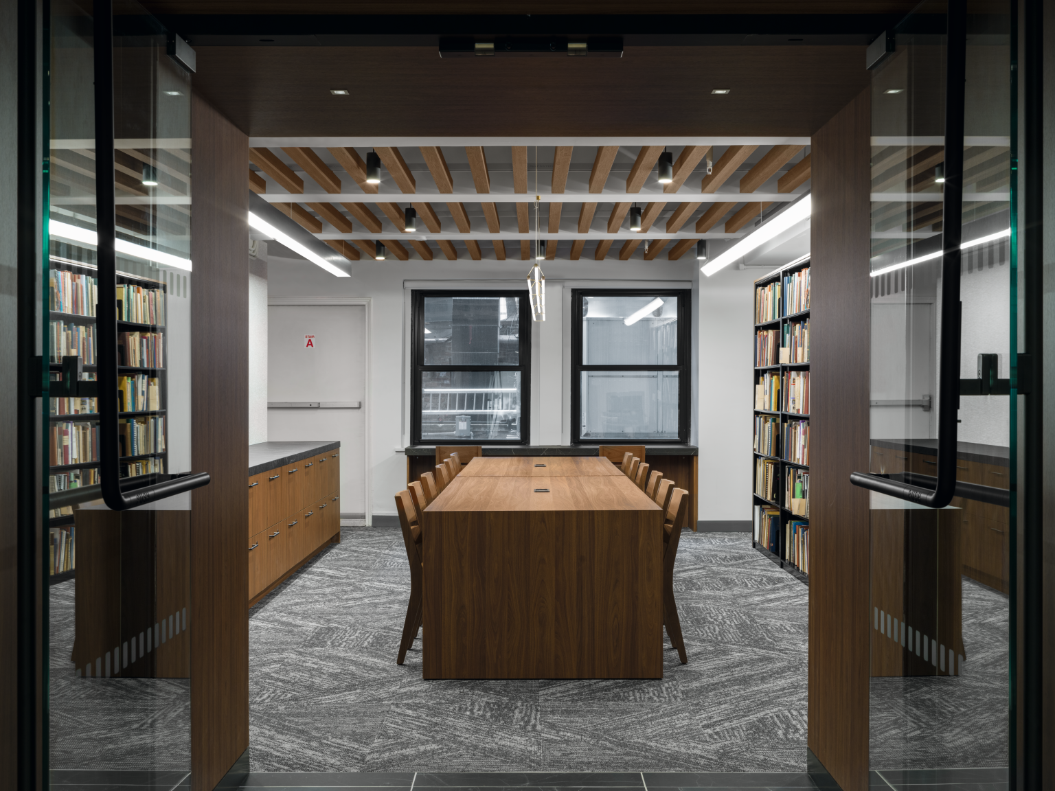 Central research table in H3791 ST12 Auburn Carini Walnut and U999 Black PM bookcases. 