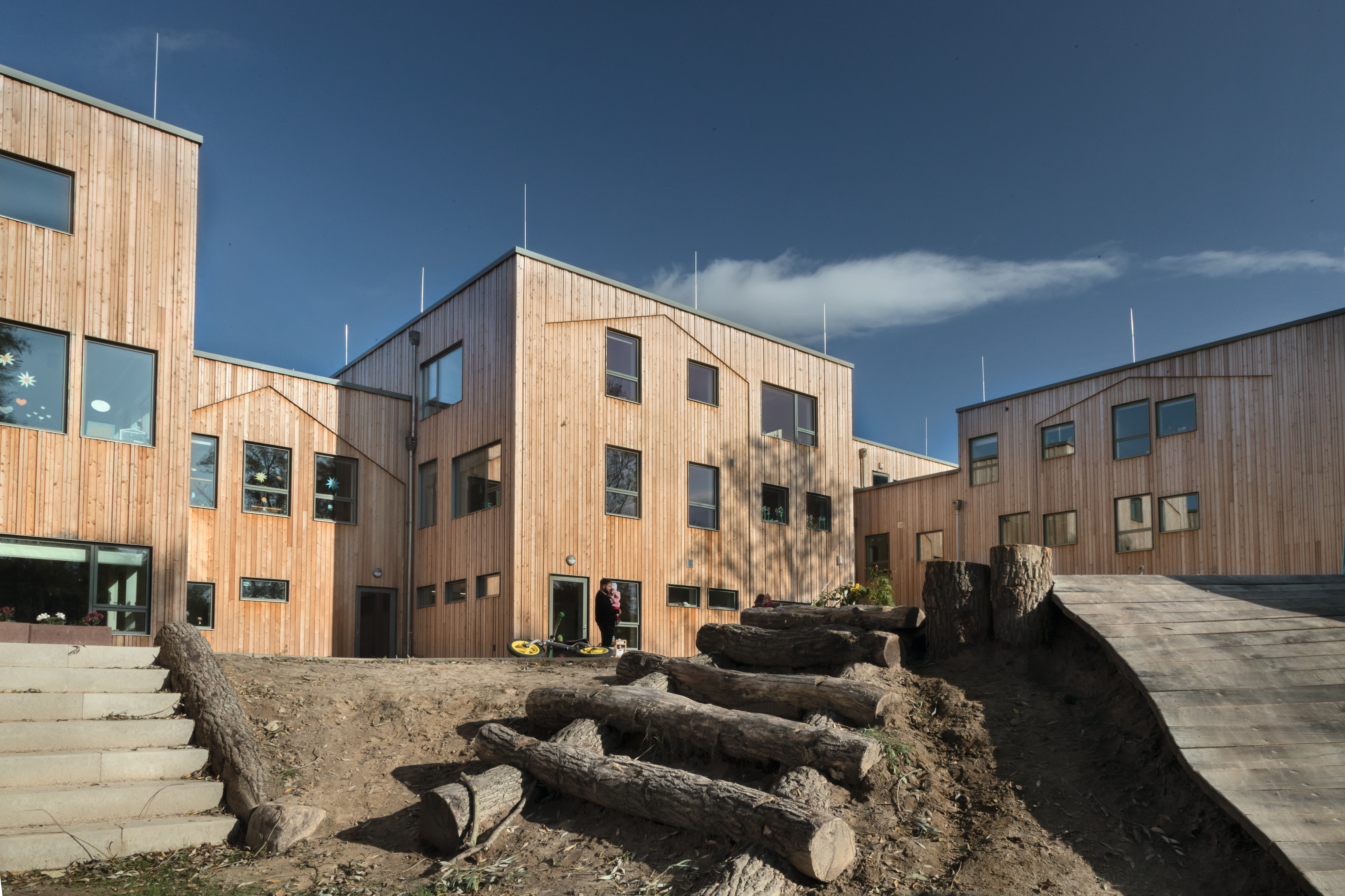 Modernes Holzgebäude mit einem Spielplatz im Vordergrund