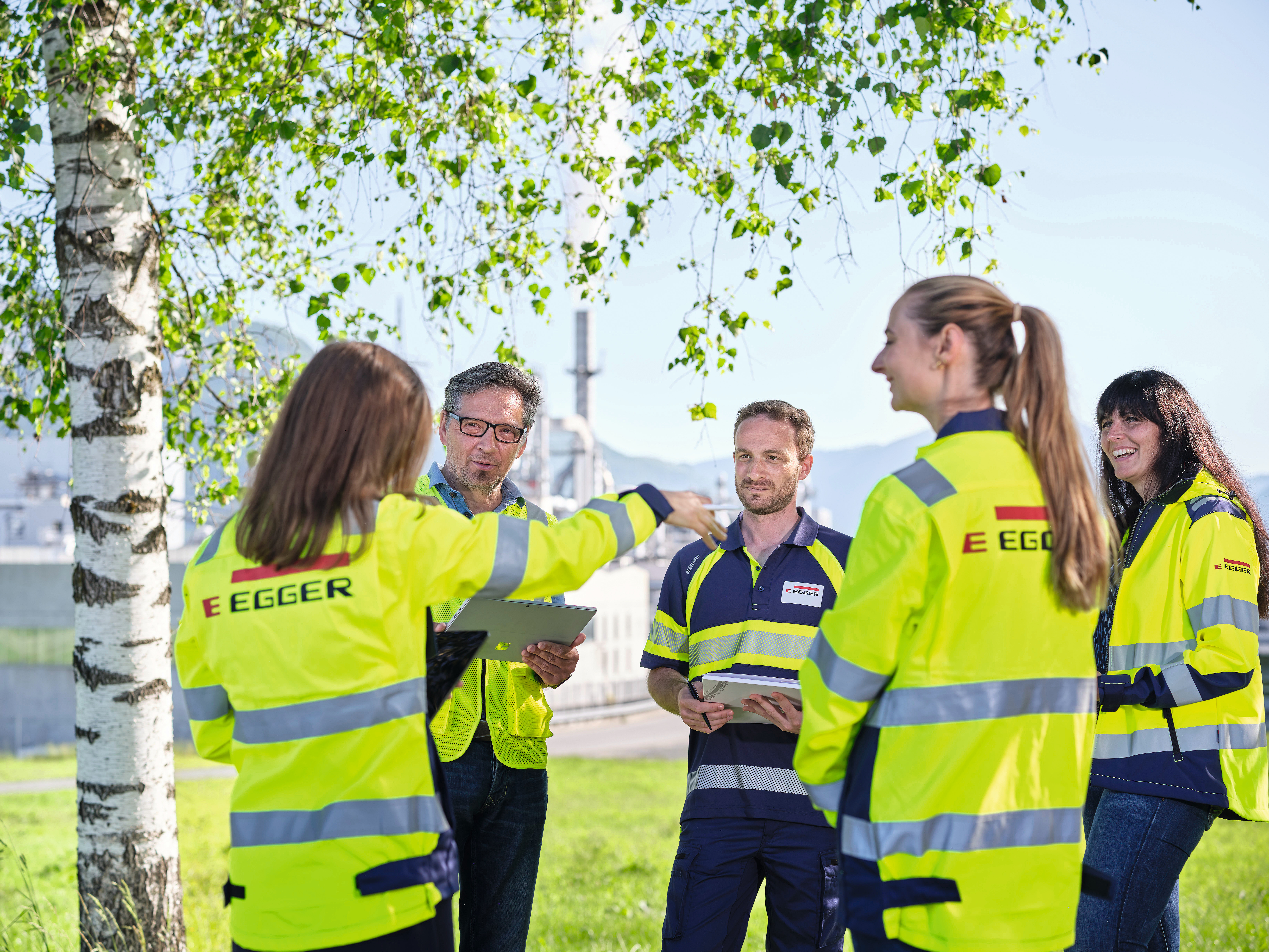 People standing talking in nature with a plant in the background