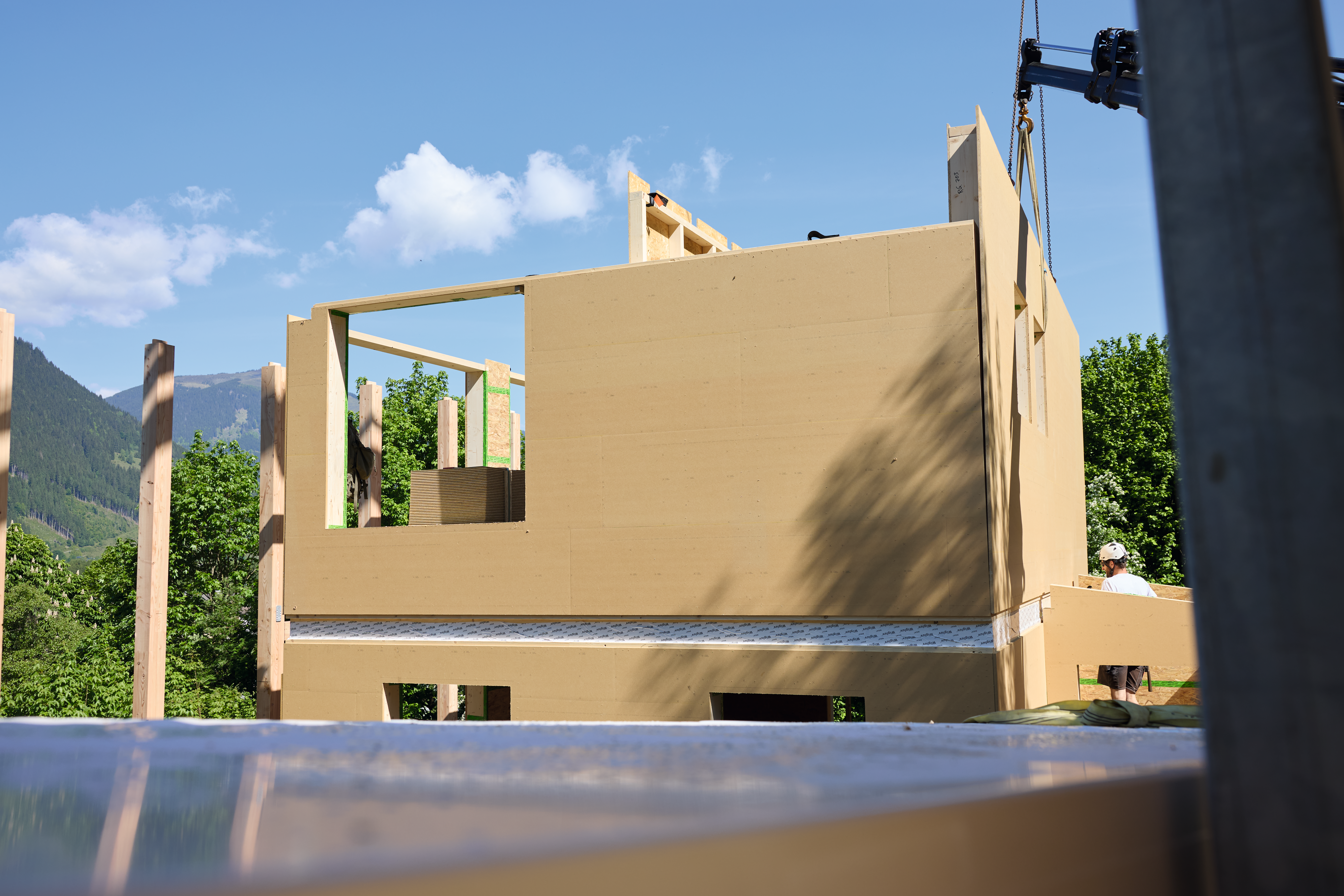 Holzbau mit vorgefertigten Wandelementen auf einer Baustelle im Grünen.