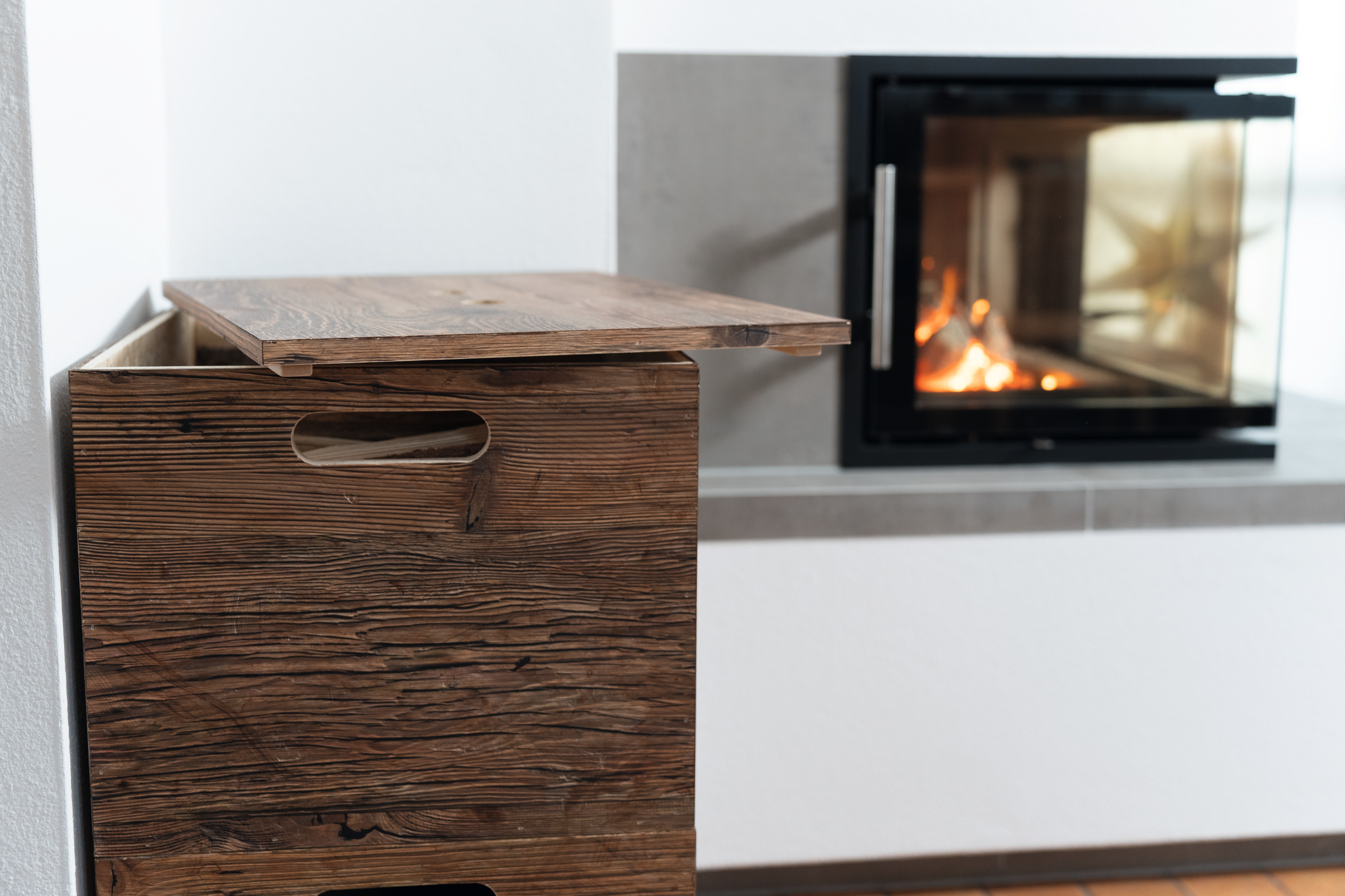 Stackable storage boxes with DecoWall surface filled with firewood, positioned next to the fireplace. 