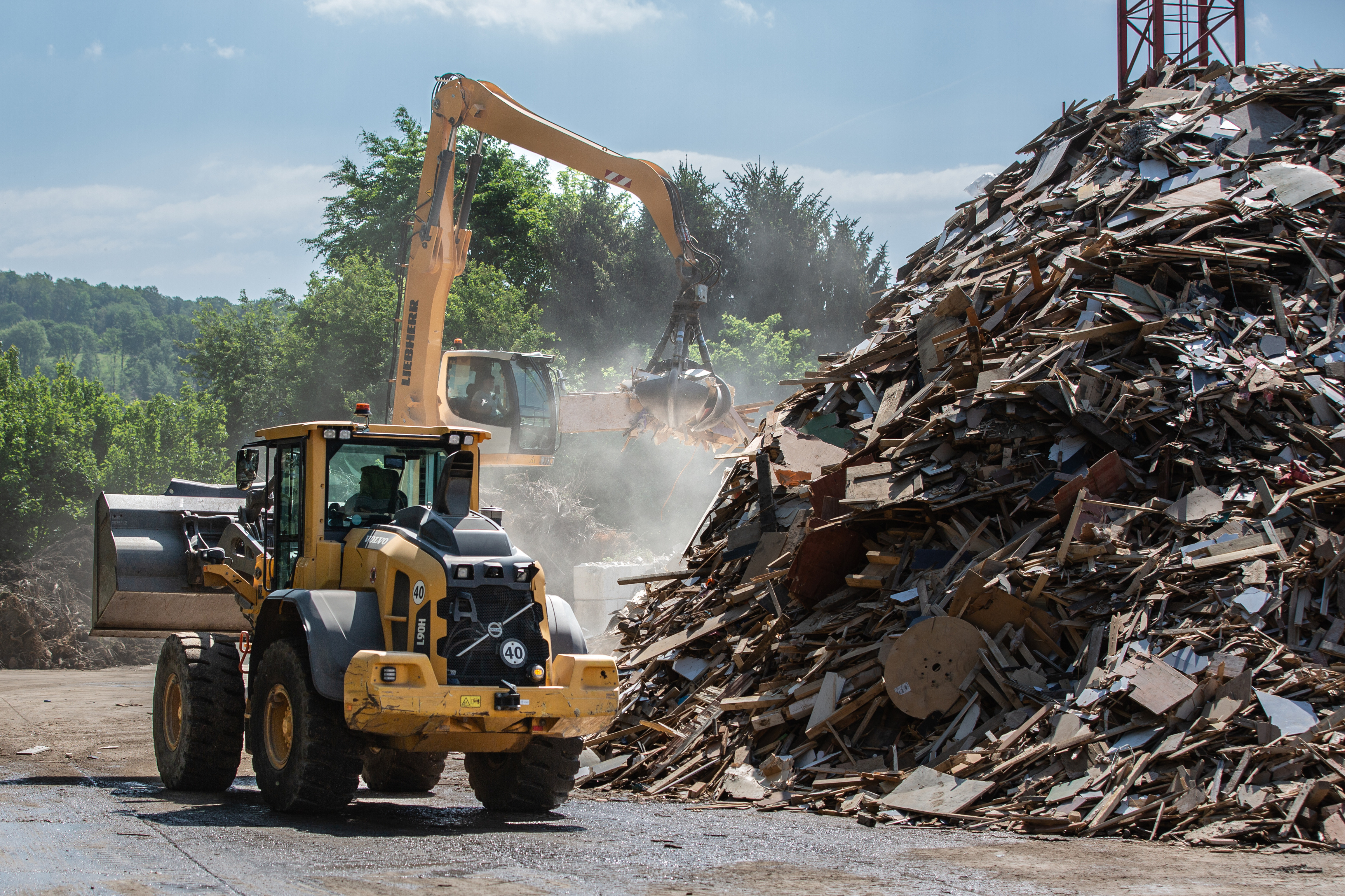 Pelleteuse et grue transportant et triant des matériaux recyclés sur le site de collecte de bois de recyclage d'Overath (Allemagne)