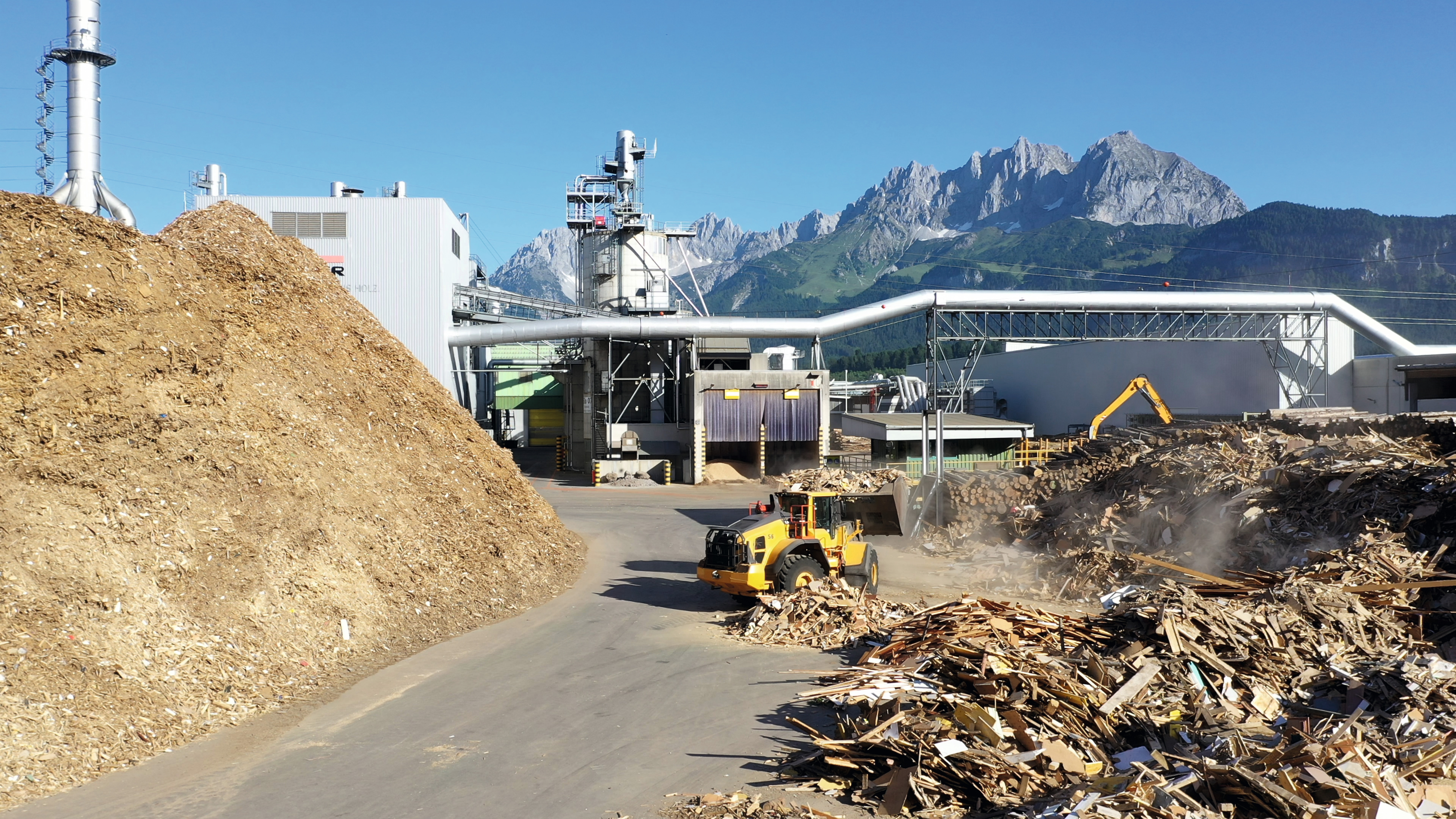 Wheel loader on a log yard with crushed wood waste and recycled material on plant premises