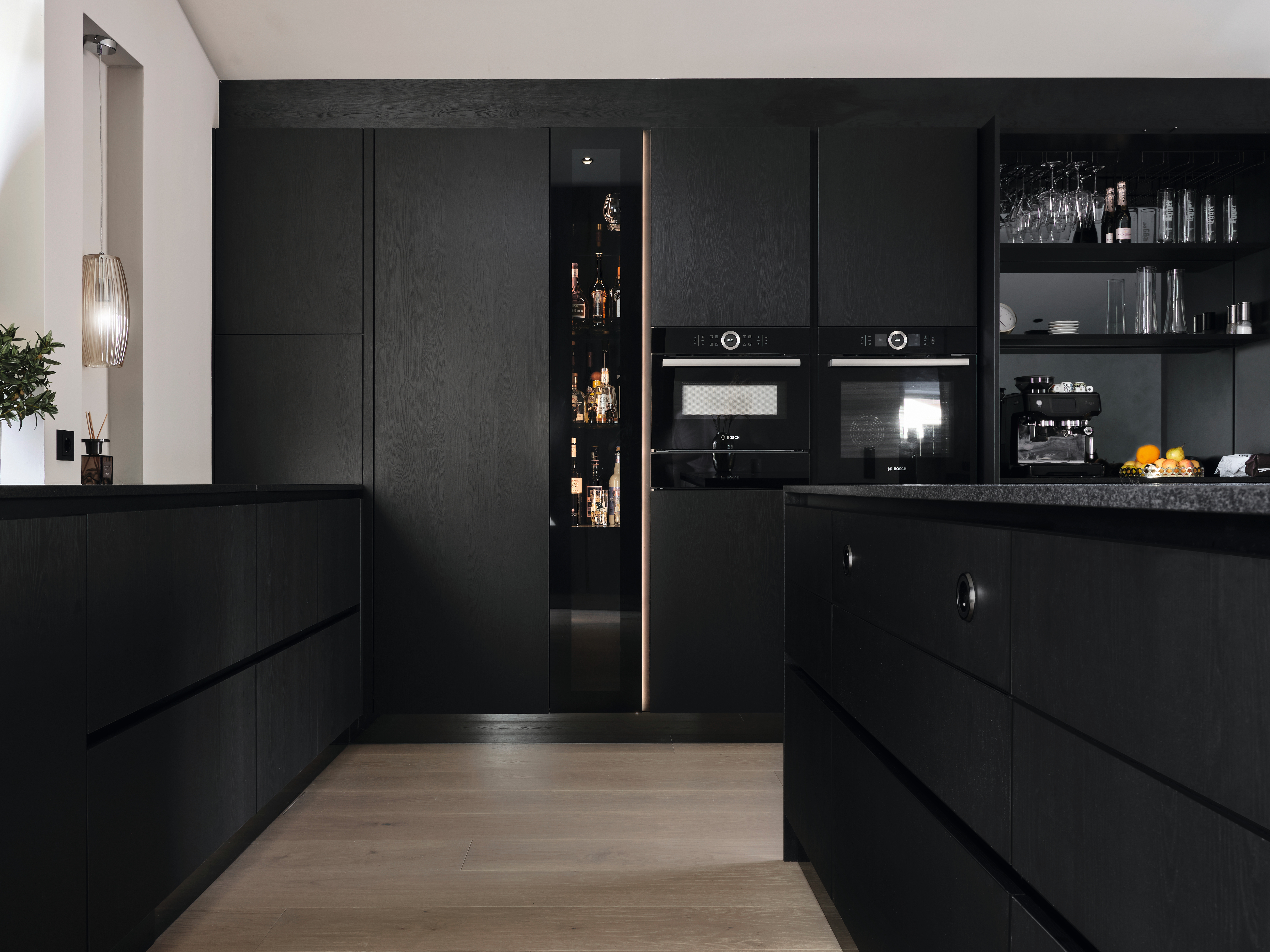 Gli elementi frontali dei mobili neri aggiungono un tocco moderno alla cucina.