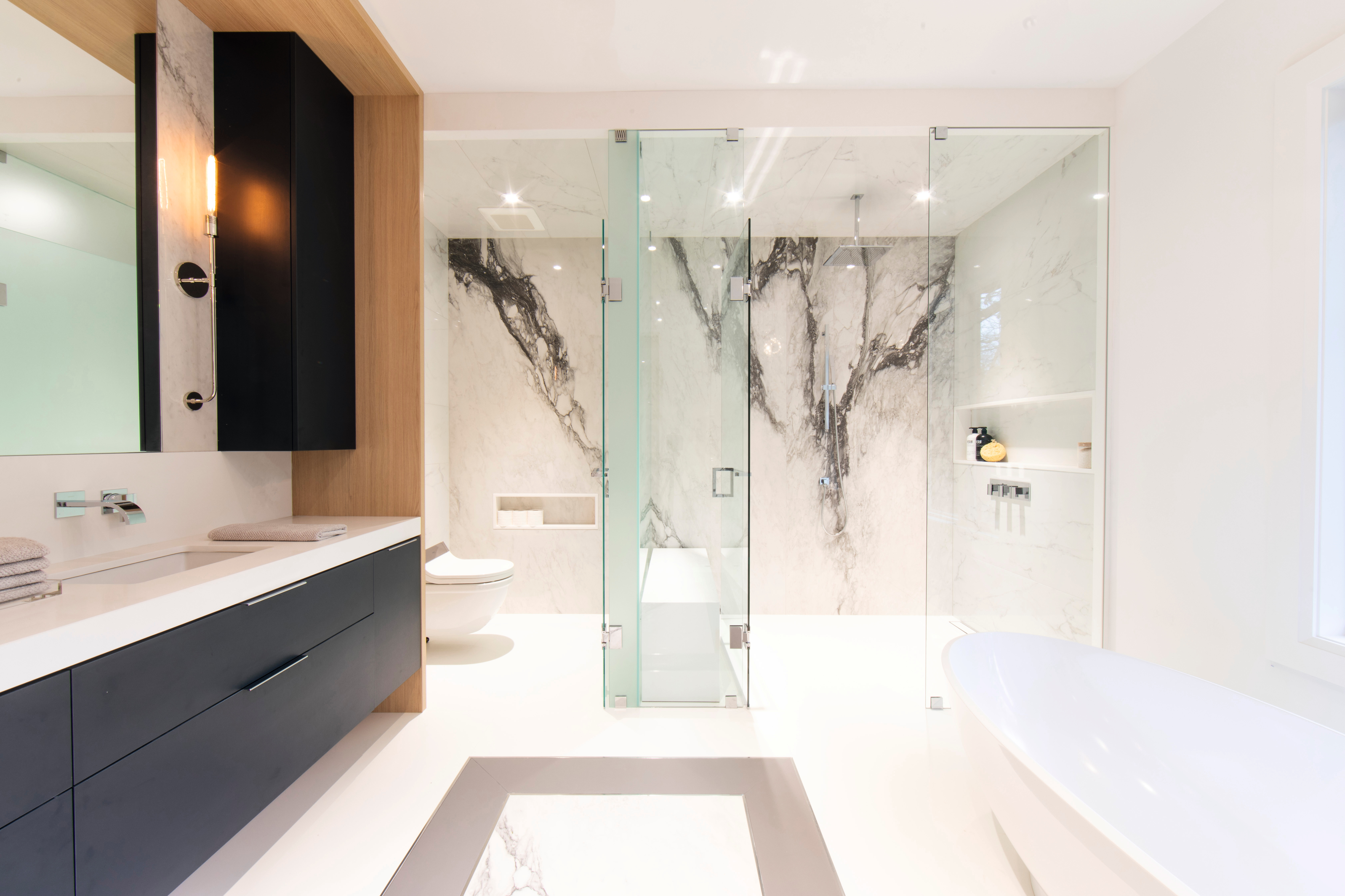 Črni detajli v kombinaciji z svetlim lesnim dekorjem in elegantnim marmorjem spremenijo kopalnico v oazo dobrega počutja.