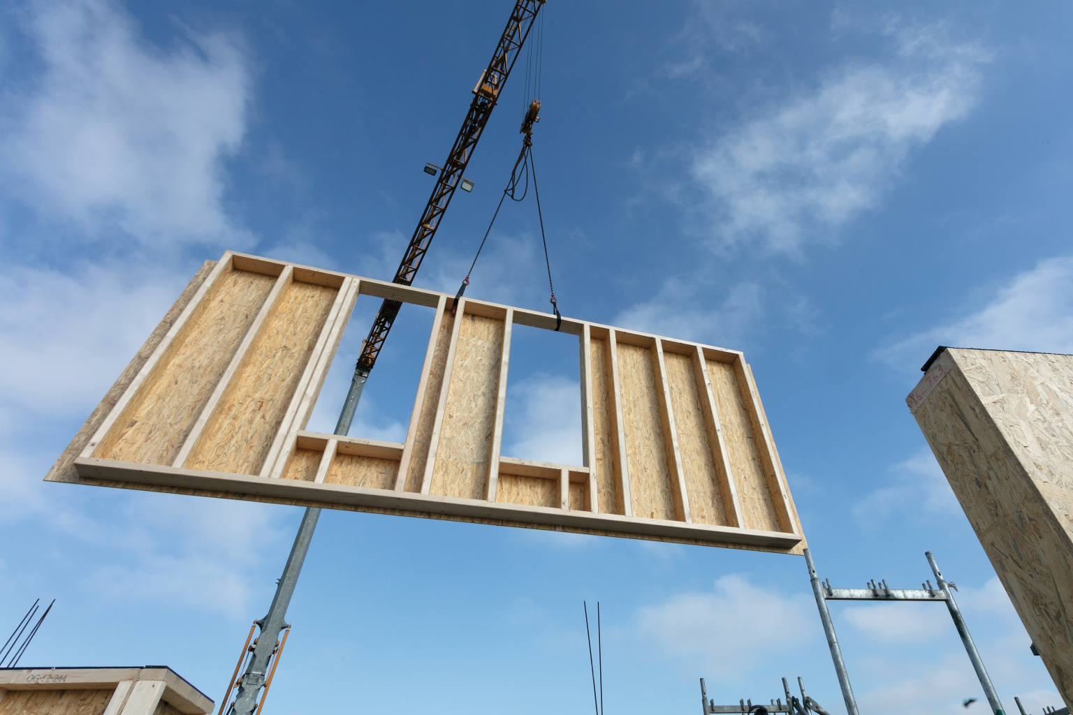 A prefabricated timber construction element containing the EcoBox is being installed on a construction site using a crane.