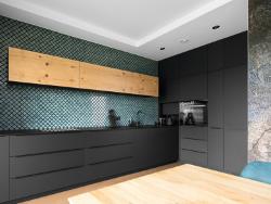 La surface noire mate contraste avec un dosseret aux couleurs vives et des tons chauds de bois pour créer un espace de cuisine accueillant.