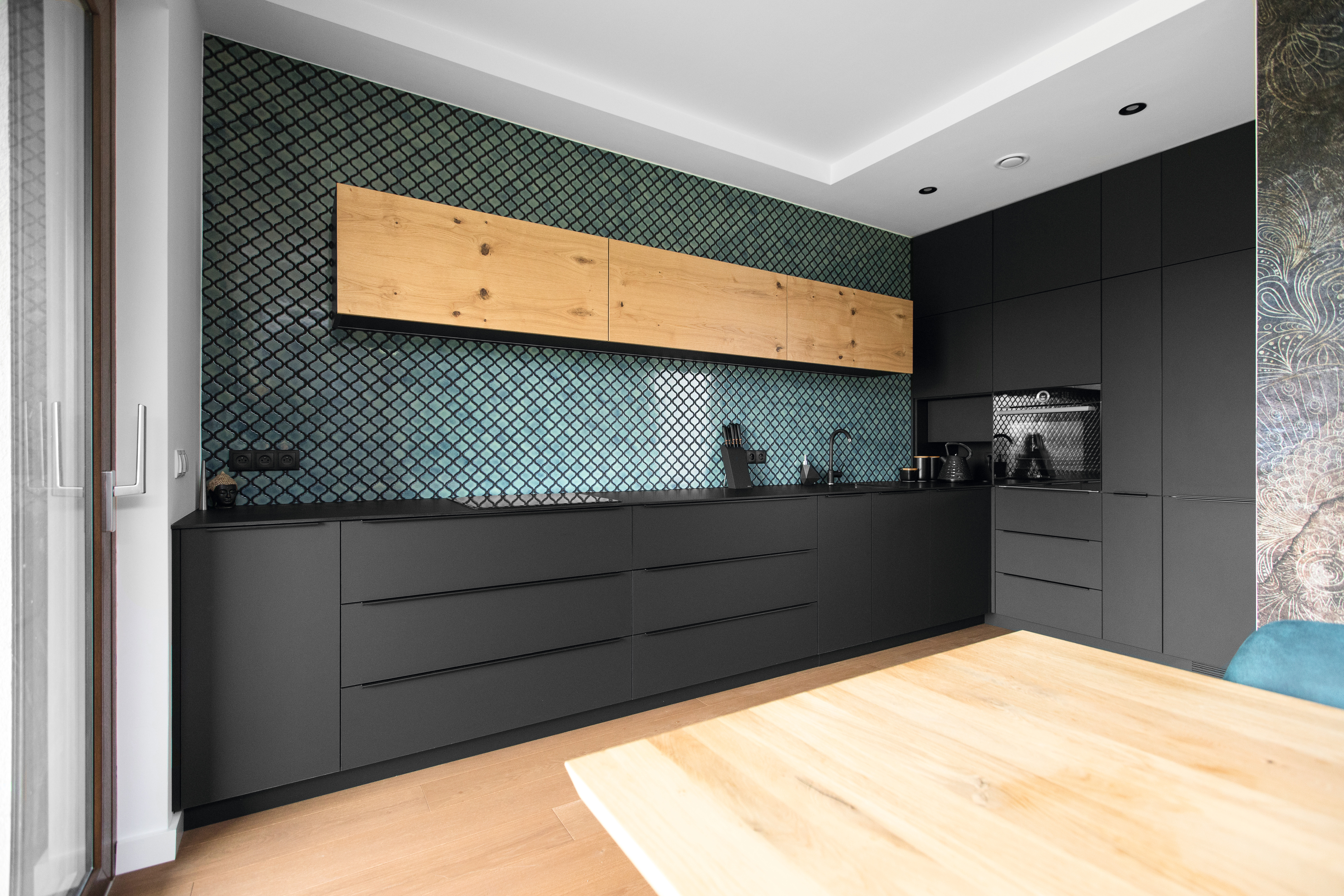 The matte black surface contrasts with a vivid backsplash and warm wood tones to create a cozy kitchen space.